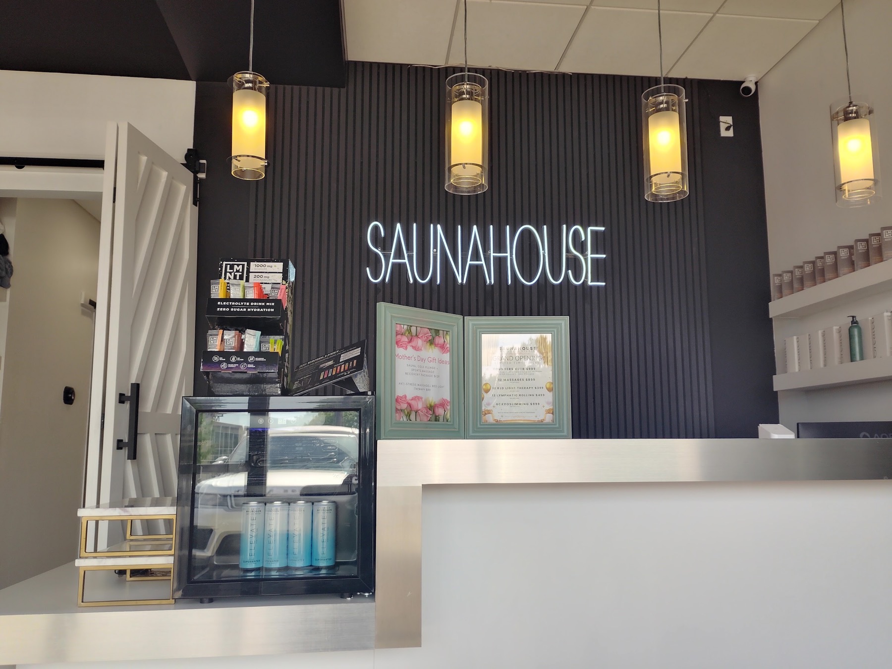 The front desk at Sauna House in Dallas, under the studio's neon sign
